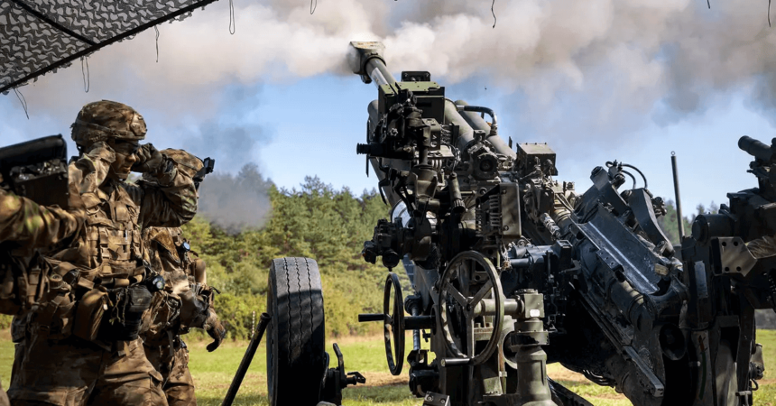 soldier covering ears firing m777 howitzer